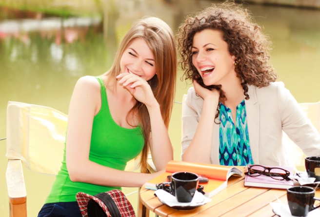 Two beautiful women laughing over a cofee